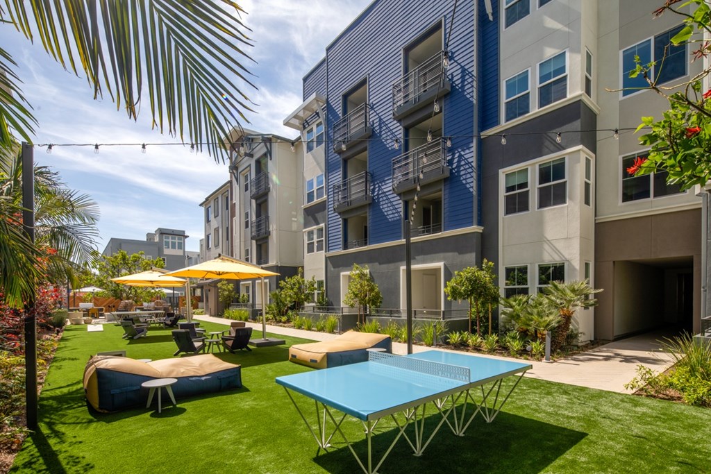 A blue pingpong table is in the middle of a grassy area.